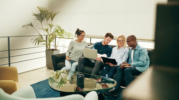 Group of young businesspeople sitting on a sofa discussing work