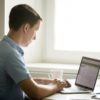 Profile portrait of young man working at desk with laptop