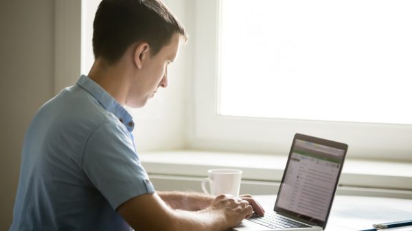 Profile portrait of young man working at desk with laptop