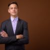 Studio shot of young handsome businessman against brown backgrou