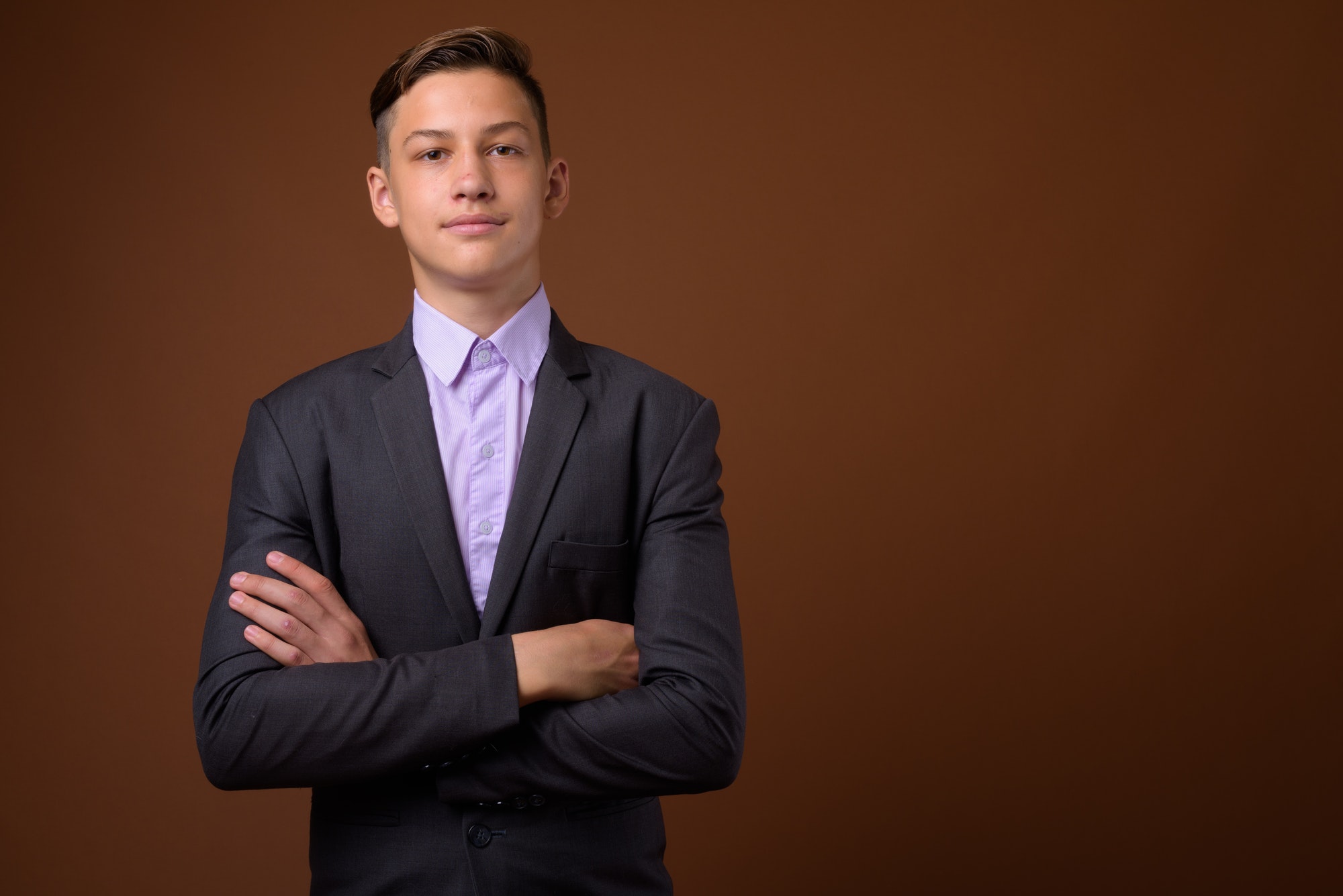 Studio shot of young handsome businessman against brown backgrou