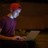 Teenage boy with a laptop in the park.