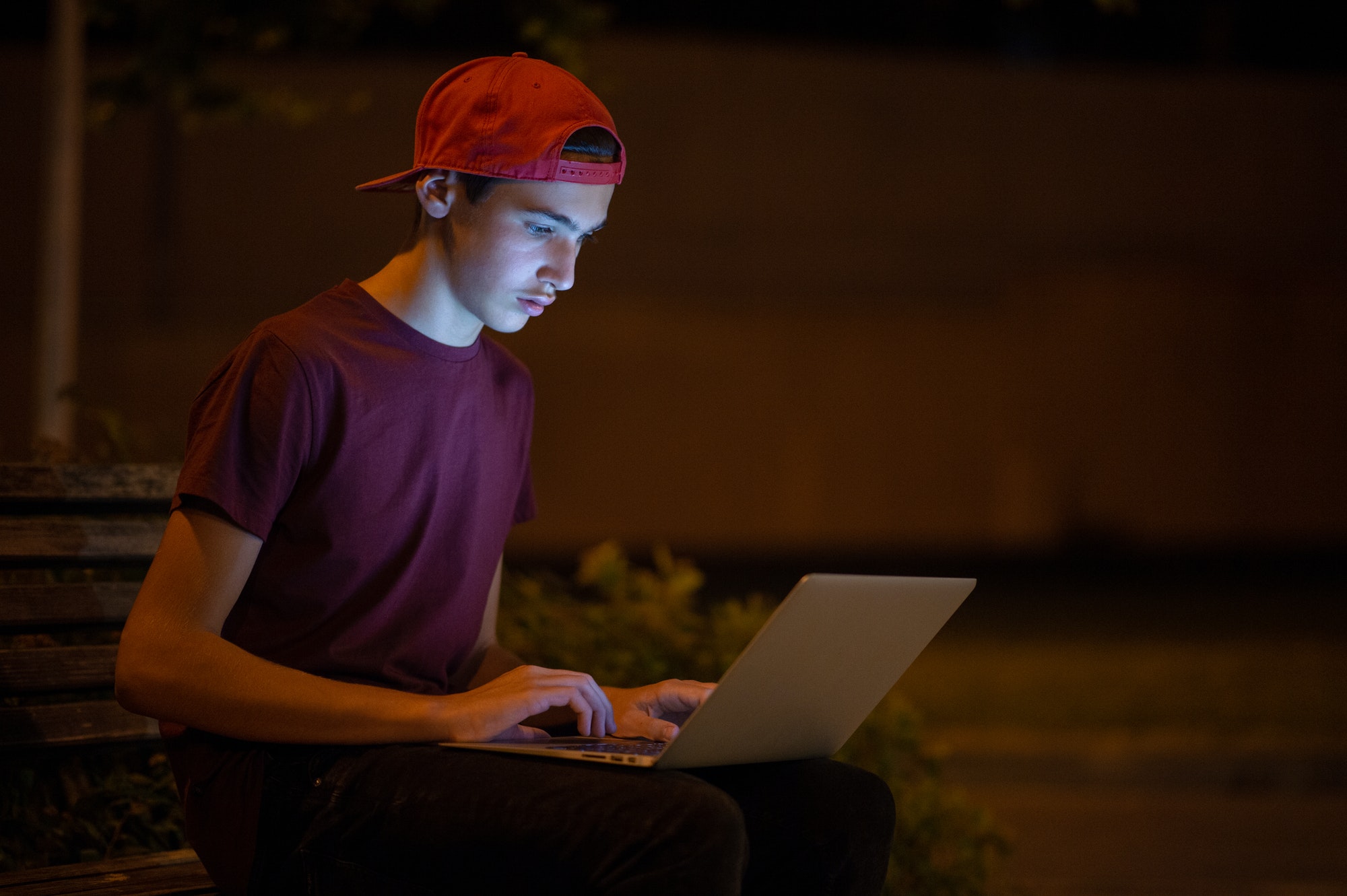 Teenage boy with a laptop in the park.