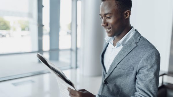 Black businessman with newspaper, office building