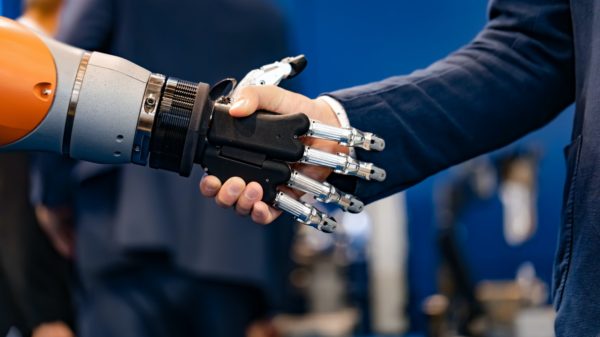 Hand of a businessman shaking hands with a Android robot.