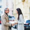 Man and woman business partners standing outdoors in city of Prague, shaking hands.