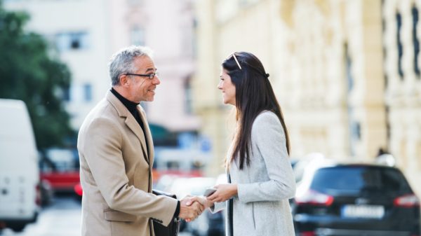 Man and woman business partners standing outdoors in city of Prague, shaking hands.