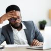 Tired african businessman sitting at workplace frustrated by business failure