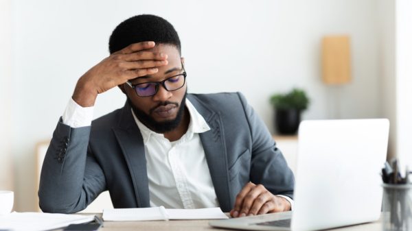 Tired african businessman sitting at workplace frustrated by business failure